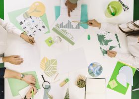 empresarios-trabajando-en-grafico-con-varios-icono-de-recursos-naturales-en-el-escritorio